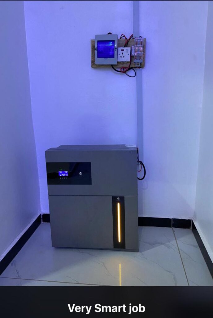 Floor standing grey solar inverter battery unit below wall mounted control box and electrical switches.