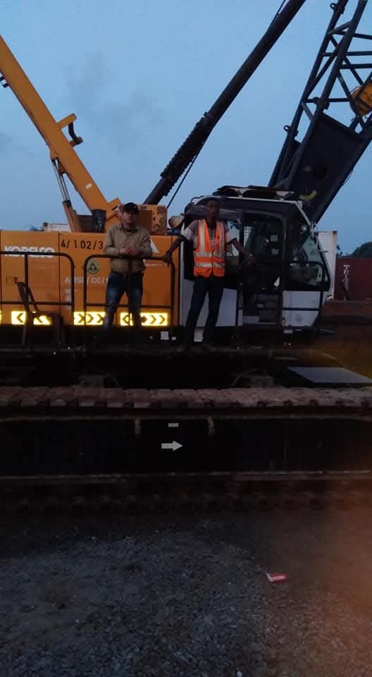 Home Workers standing on crawler crane equipment at a site.