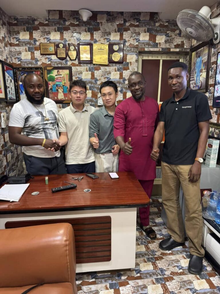 Five corporate partners shaking hands and giving thumbs up inside an office setting.